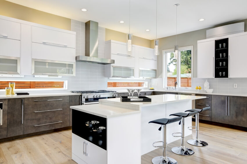 Stunning kitchen with wooden floors, white island with stools, pendant lights and steel stove with range hood