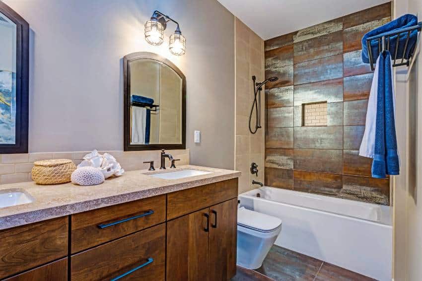 Stylish bathroom interior with double vanity cabinet, natural stone tiled floor, and wood accent wall