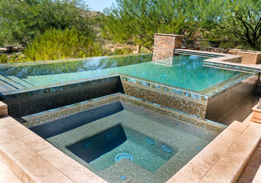 Swimming pool with pebble aggregate finish, plaster, and tile deck