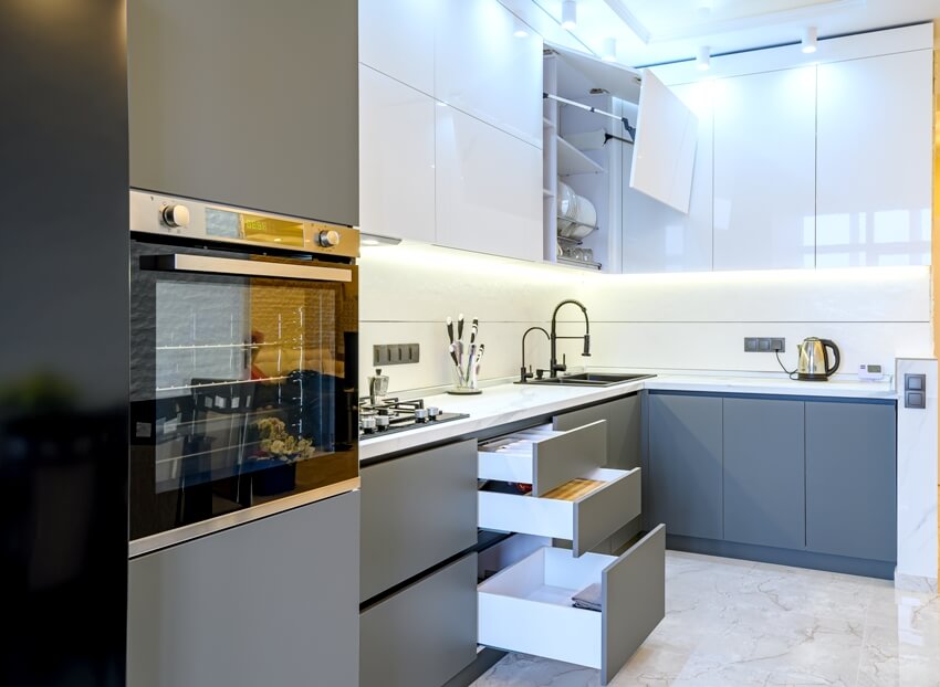 White and dark grey modern kitchen interior with dining table, some furniture, open drawers and doors 