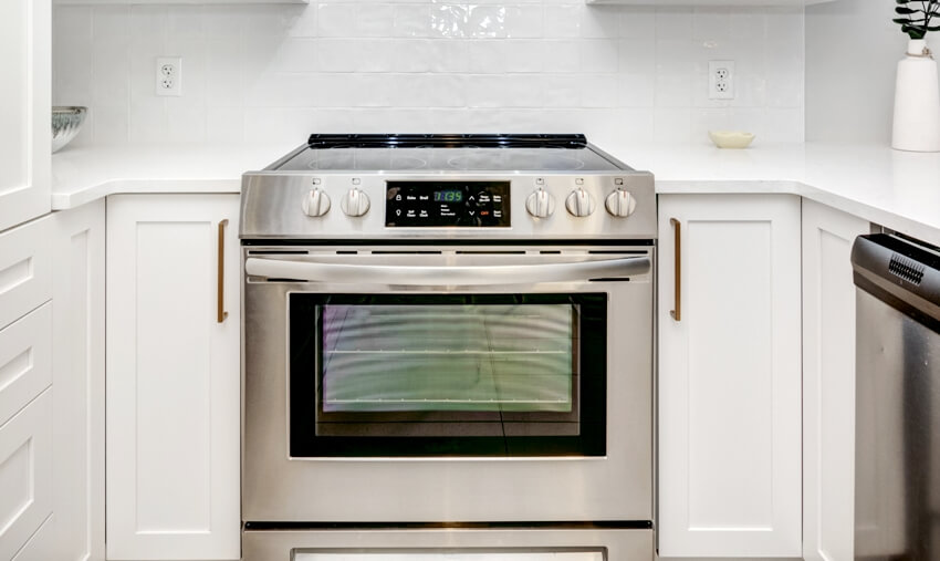 White kitchen interior with steel gas range with oven