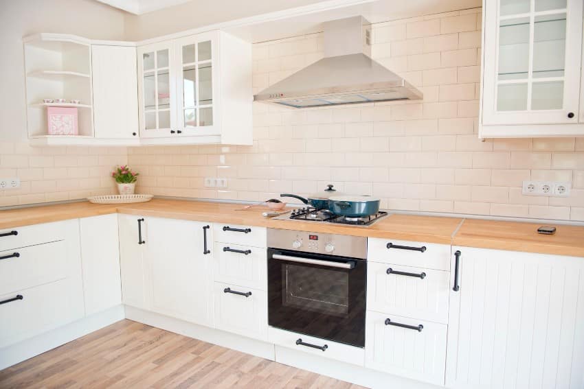 White kitchen interior with subway tiles backsplash, wooden countertop and grooved kitchen cabinets