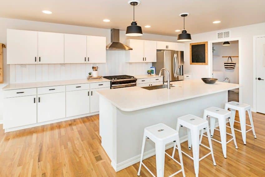 White kitchen with hardwood flooring, shiplap tile backsplash, pendant lights and various shades of brown