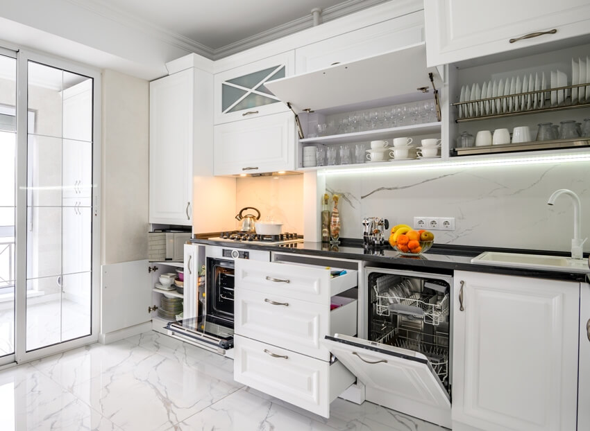 White modern kitchen interior with open cabinets, pulled out drawers and open dishwasher