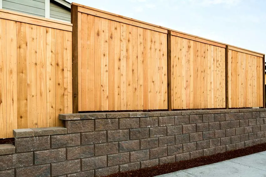 Wood side by side fence constructed on top of a retaining wall