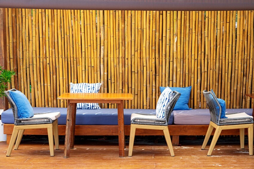 Wooden furniture, rattan chairs and bamboo wall with blue pillows and sofa