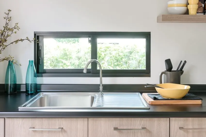 Wooden kitchen counter with black granite on top and clean stainless sink