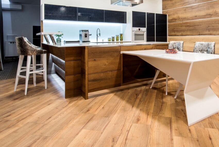 Wooden kitchen interior with table, seats, island and laminate flooring