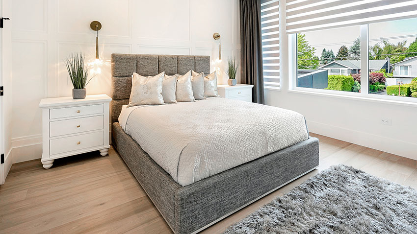 Bedroom with grey bed, white cabinet and French windows with blinds