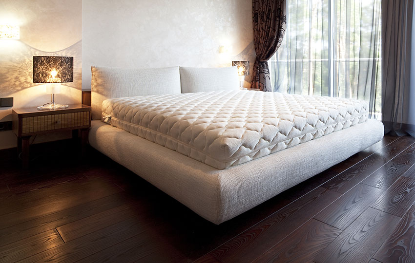 Bedroom with box spring bed, floating table and dark wood flooring