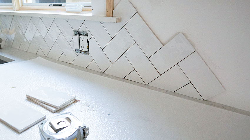 Installing herringbone tile backsplash in kitchen