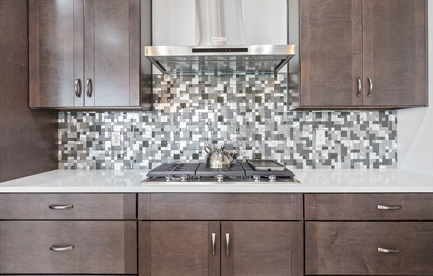Kitchen with mosaic design backsplash range hood white countertop