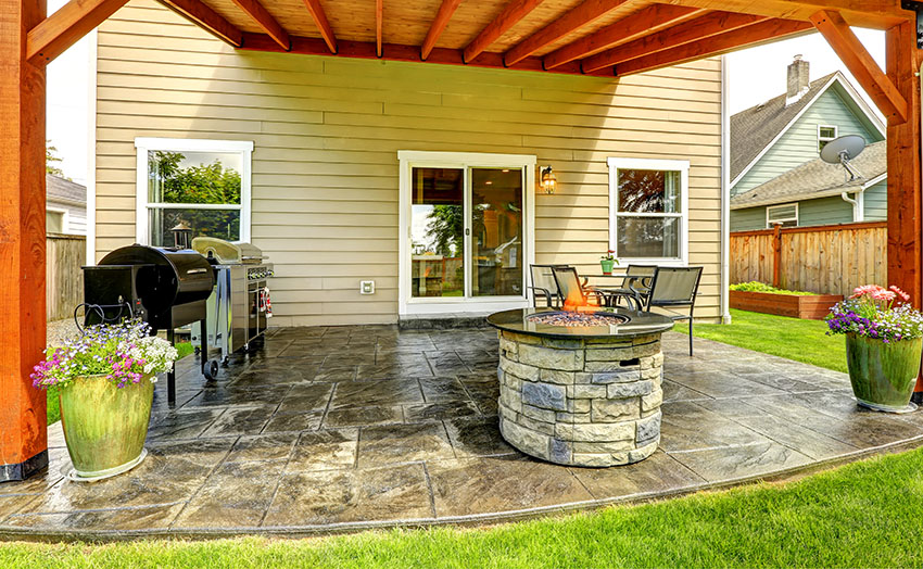 Pergola with stone pavers flooring sliding French door round firepit clapboard sidings griller
