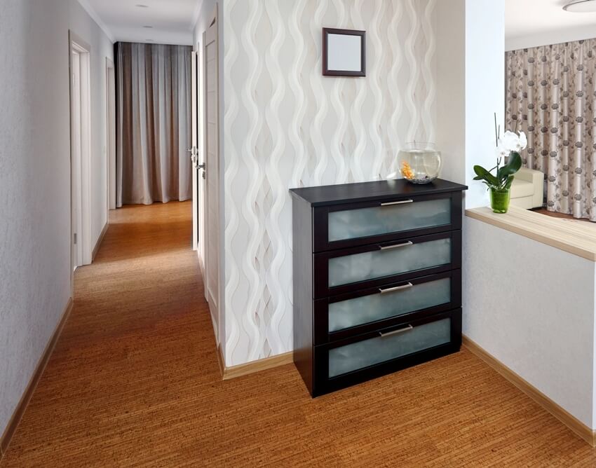 A view of hallway with wooden cabinet, bar counter with orchid and cork flooring