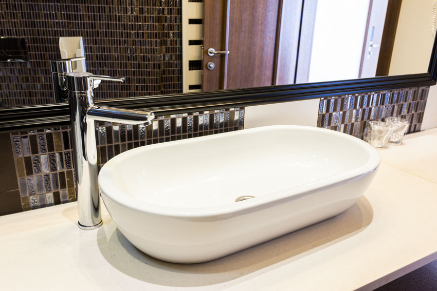 Bathroom vanity with kit kat mosaic tile backsplash, sink, faucet, countertop, and mirror