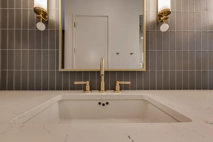 Bathroom vanity with kit kat tile backsplash, sink, mirror, and wall mounted lights