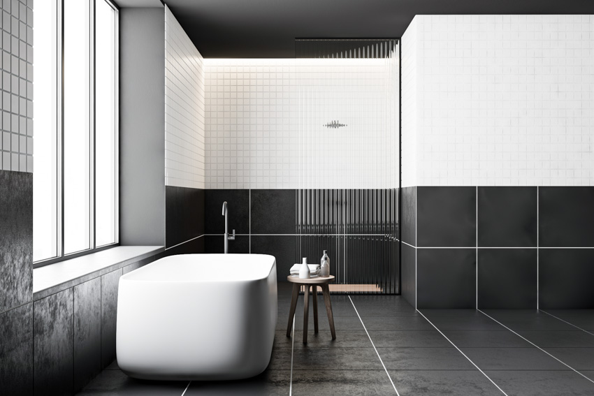 Bathroom with black terracotta floor tiles, tub, stool, and window