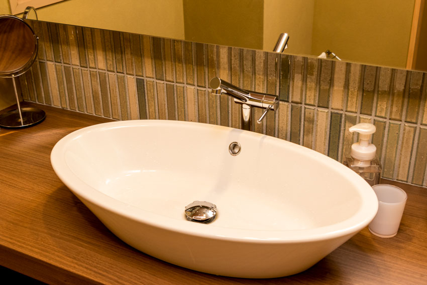 Bathroom with mirror, basin sink, mini kit kat tile backsplash, faucet, and wood countertop