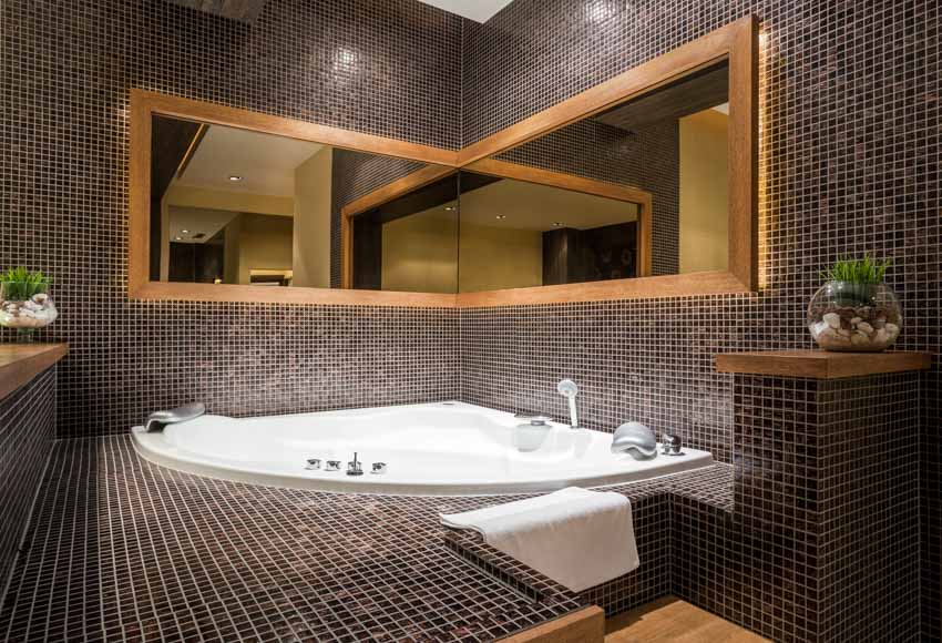 Bathroom with tub black mosaic floor tiles, mirror, and indoor plants