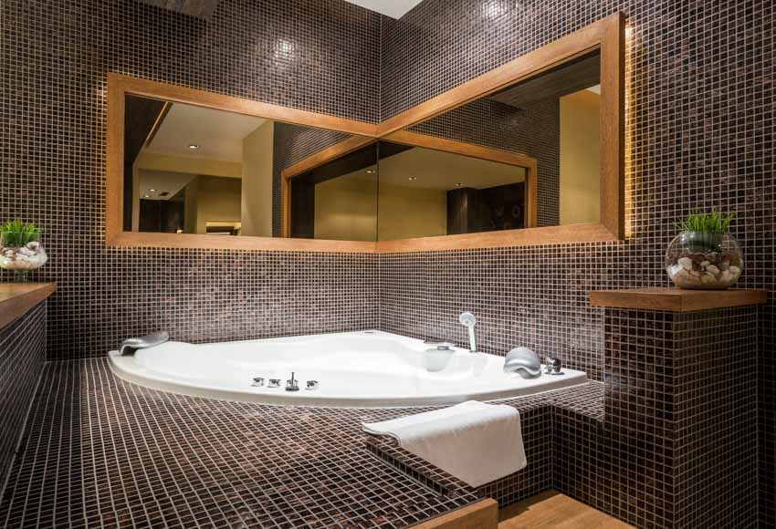 Bathroom with tub, black mosaic tiles, mirror, and indoor plants