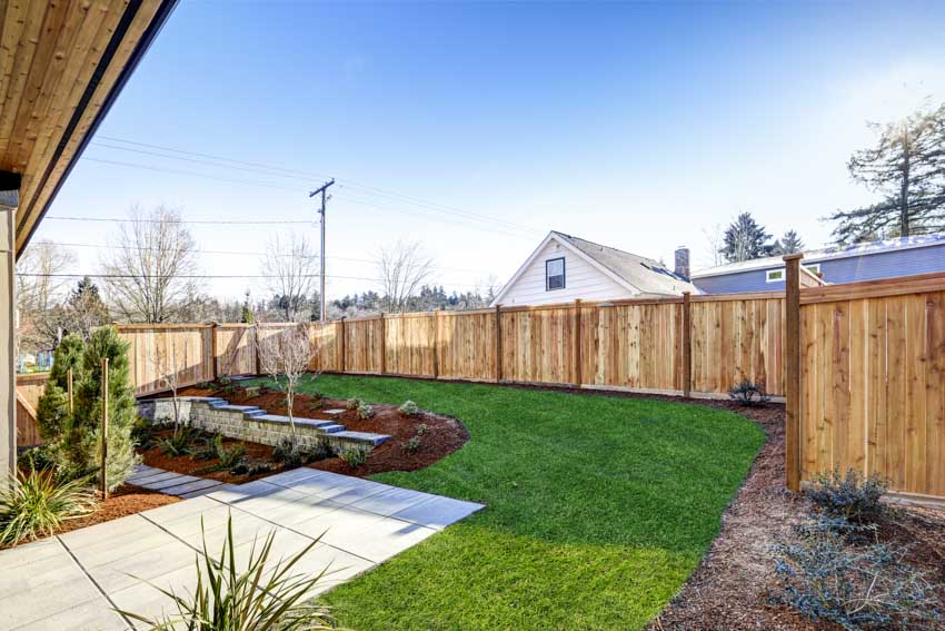 Beautiful backyard with concrete walkway, plants, and cedar fences