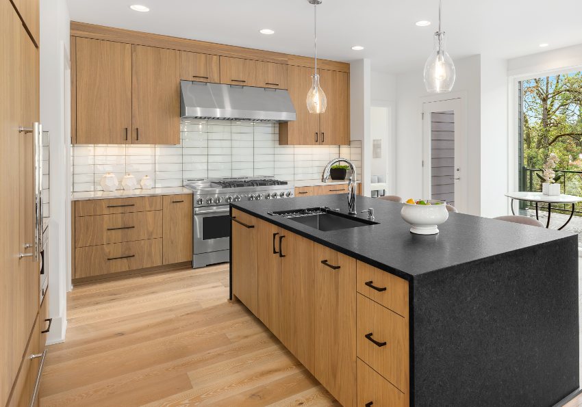 Beautiful kitchen in new luxury home with back veneer plywood cabinets, waterfall quartz island, pendant lights and hardwood floors