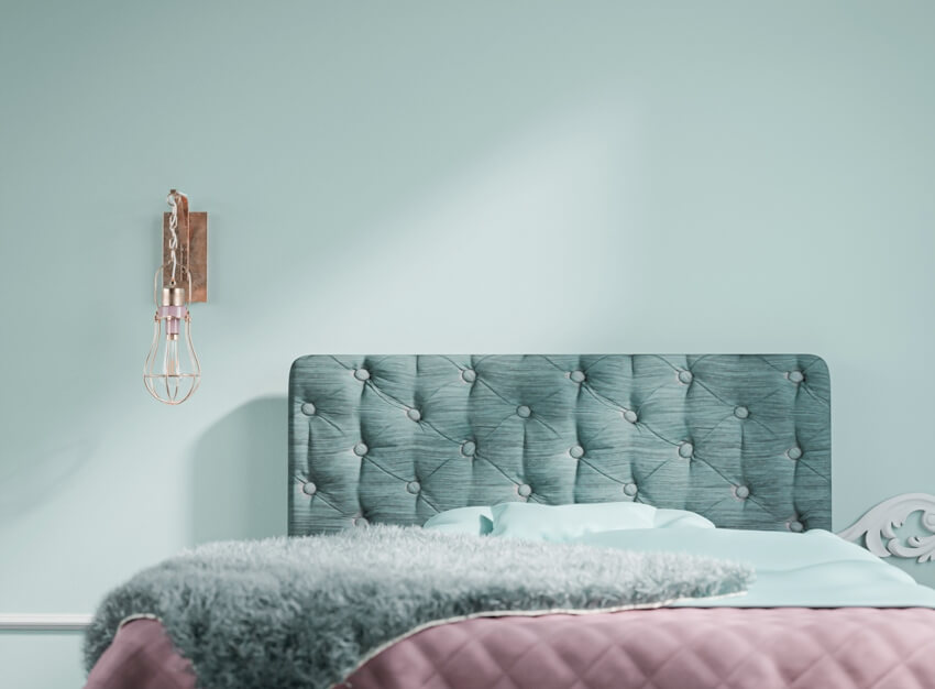 A cozy bedroom with a double bed and turquoise walls with modern metallic gold light fixture