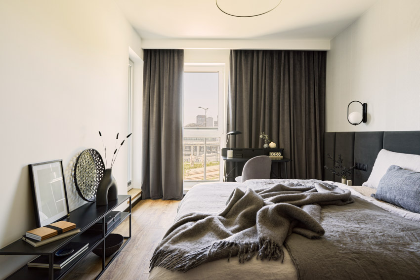 Bedroom with comforter, pillows, console table, wood floors, and portable blackout curtain