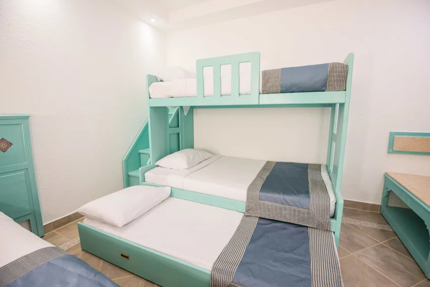 Bedroom with triple bunk bed, mattresses, pillows, and comforters