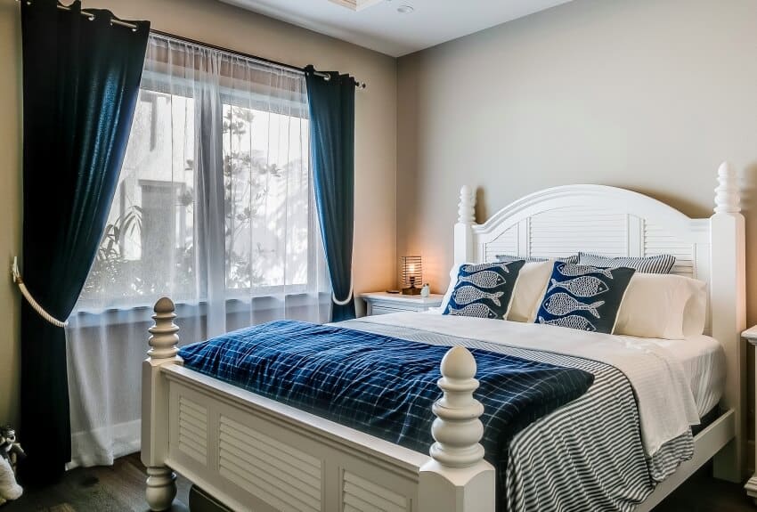 Bedroom with white bed and blue stripes sheet, blue silk and sheers on windows