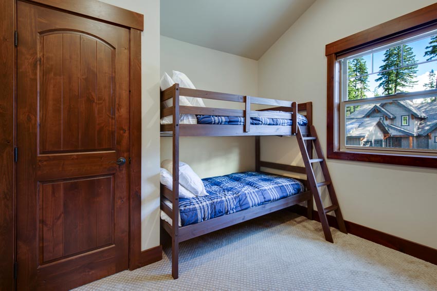 Bedroom with wood bunk bed, blue mattress, pillows, door, and window