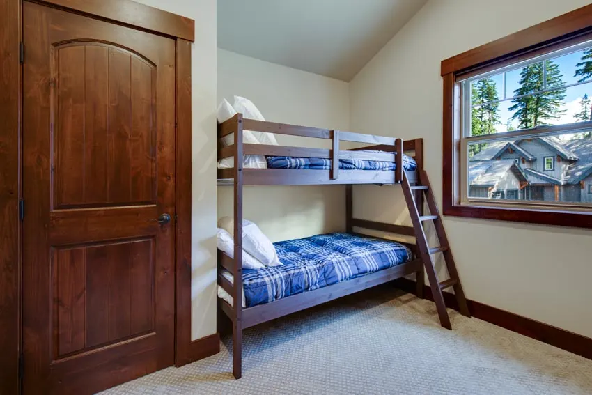 Bedroom with wood bunk, blue mattress, pillows, door, and window
