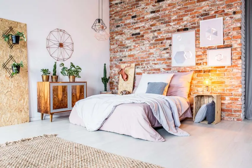Bedroom with wood crate nightstand, brick accent wall, dresser, comforter, pillows, and rug