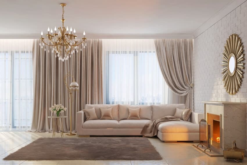 A bright with beige tones and cozy room with chandelier, decorative curtains, fireplace and mirror