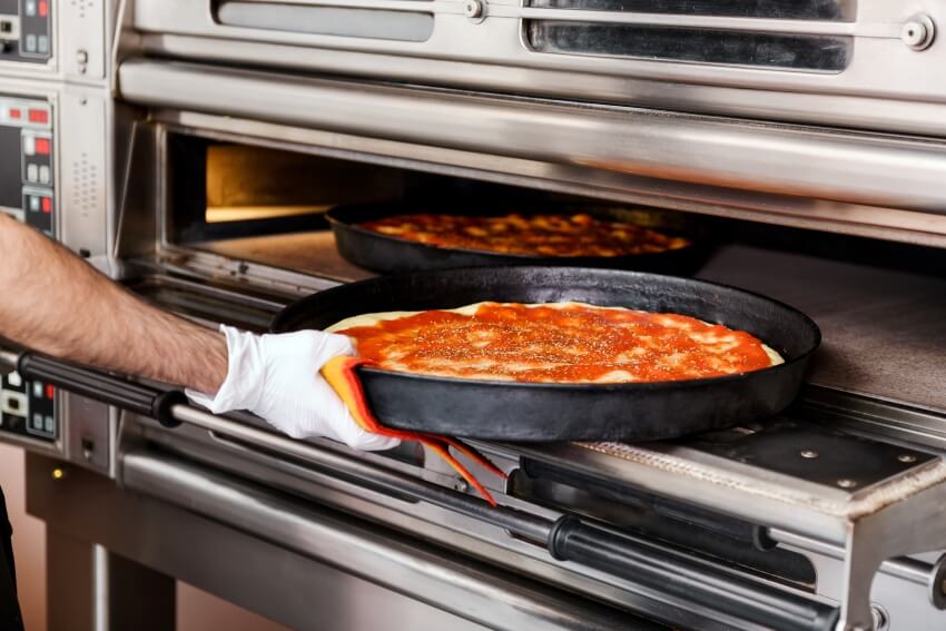 Baking pizza on a baking tray into pizza oven