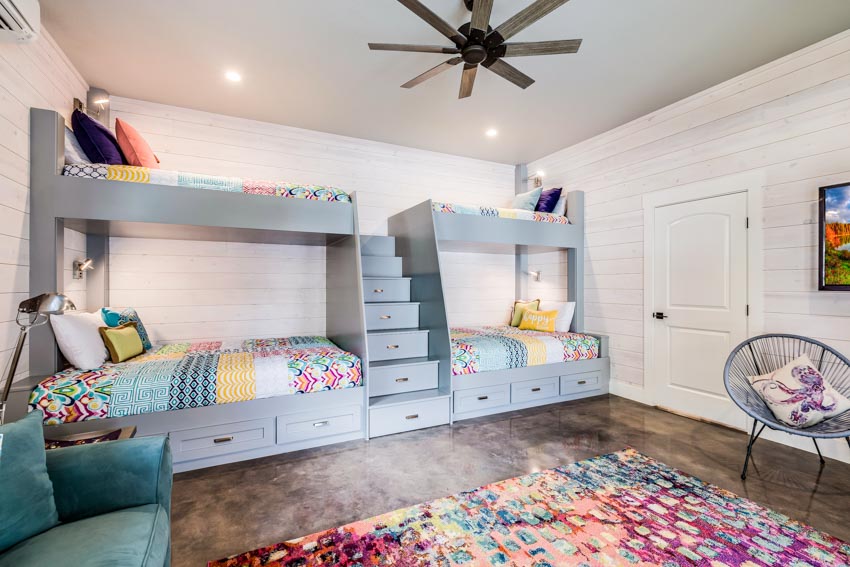 Children's bedroom with bunk bed storage, drawers, rug, wood floor, ceiling lights, mattresses, and chair