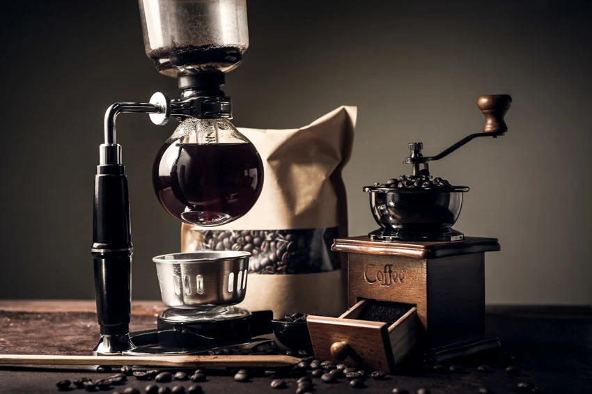 Classic coffee maker with grinder, and coffee beans on top of wood table