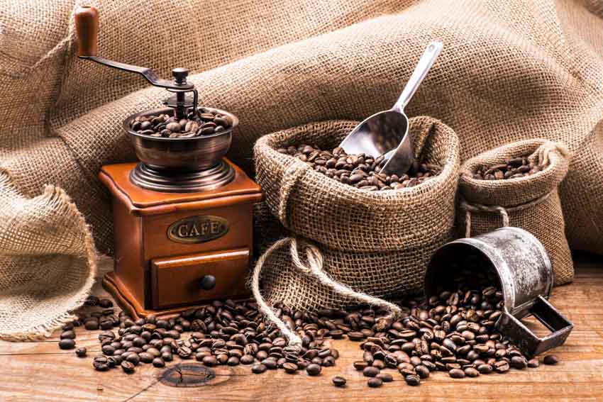 Coffee grinder and bags of coffee beans on wood surface