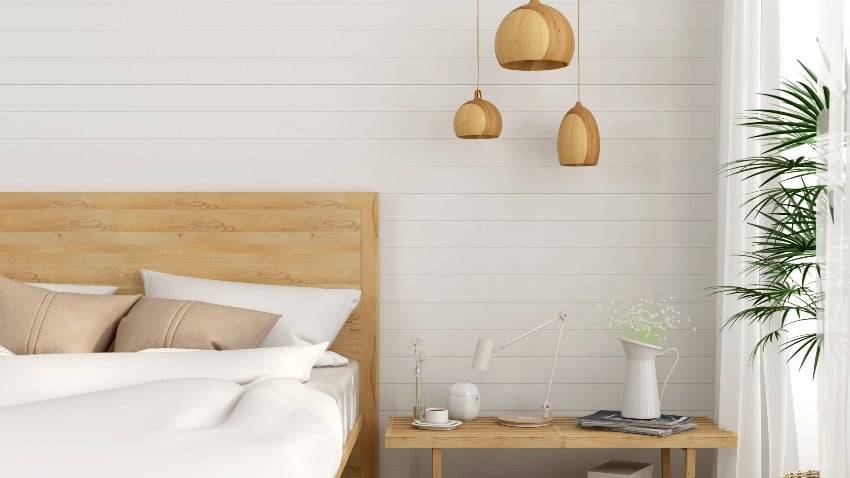 A cozy bedroom with white horizontal shiplap walls and wooden décor