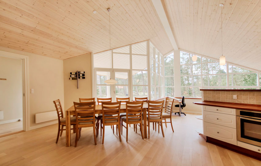 Dining room with tongue and groove ceiling board, table, chairs, wood floor, and windows