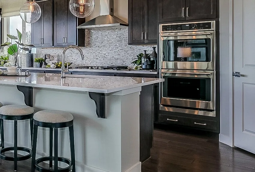 Double wall oven, kitchen island with stools and mosaic backsplash in an elegant kitchen