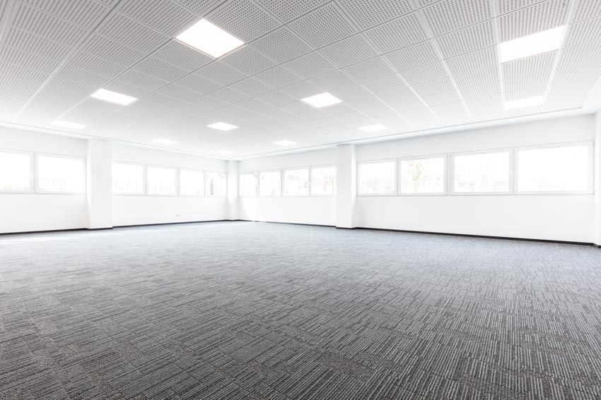 Empty room with carpet floor, windows, and ceiling metal panels
