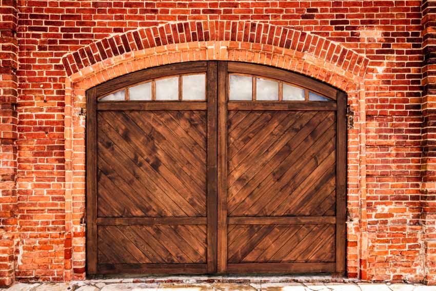 Farmhouse garage with wooden doors, and brick wall