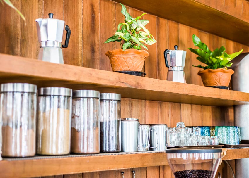 Floating shelves with coffee related accessories, supplies, and indoor plants on it