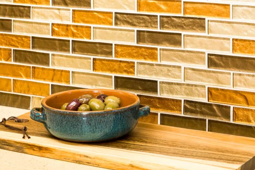Glass tiles made of different colors, bowl with fruit and wood counter