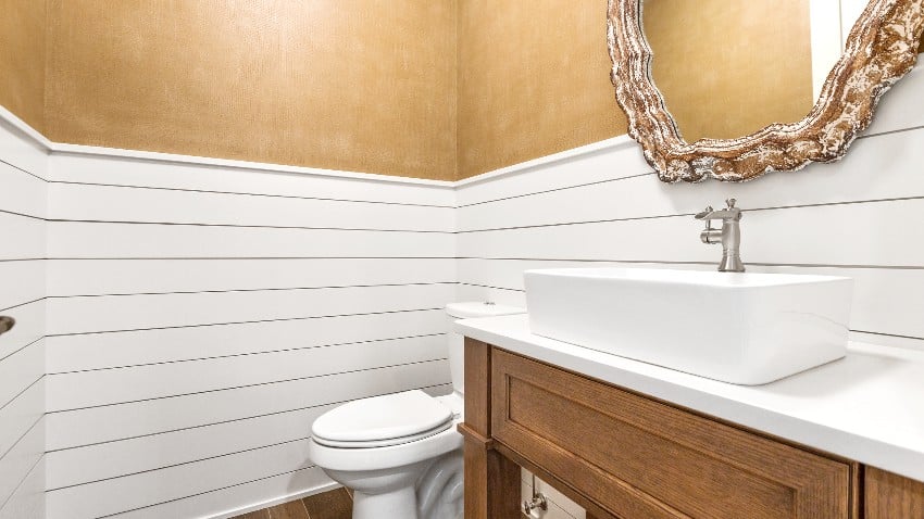 Powder room with gilded mirror, white toilet and ceramic basin