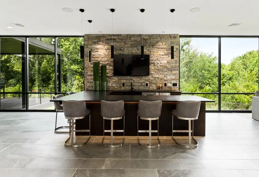 Dark wood bar with stone accent wall, bar chairs and picture windows