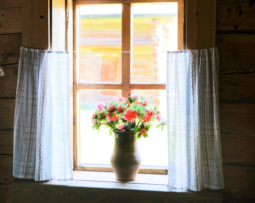 Home interior with casement window, vase, flowers, and tier curtain