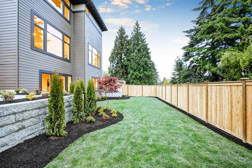 House exterior with backyard, siding, hedge plants, grass, and cedar fences