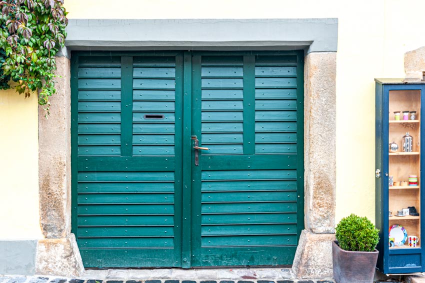 House exterior with green louvered garage doors, and plants